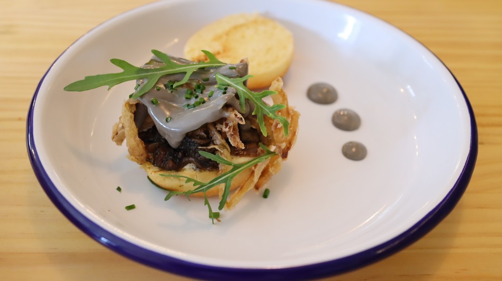 Minibrioche de guiso de calamar con alioli negro, chipotle, lima y cebolla frita